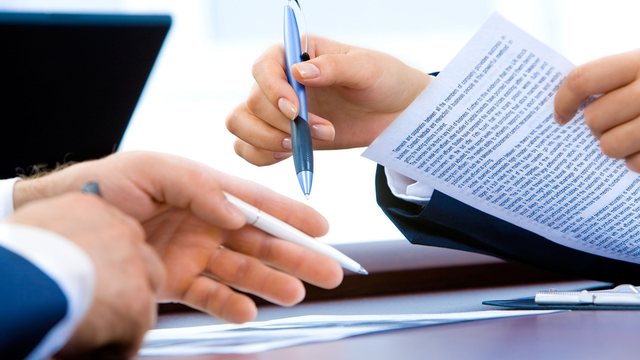 Zwei Personen unterschreiben einen Vertrag im Büro